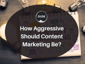 1 Front image of a blog titled "How aggressive should content marketing be? "with notebook written " Content marketing " as the background and the title displayed in corporate typography